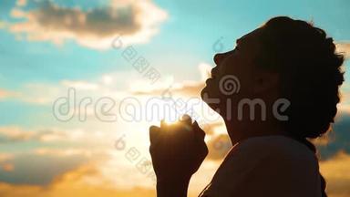 女孩在祈祷。 女孩在日落时交叉双手祈祷剪影。 慢生活方式运动视频。 女孩双手合拢